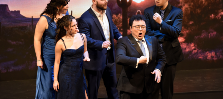 Five Marion Roose Pullin Arizona Opera Studio Artists—Sedona Libero, Francesca Herrera, Sam Krausz, Wanchun Liang, and Yichen Xue—perform a dramatic ensemble scene on stage with a desert sunset and saguaro cactus backdrop.